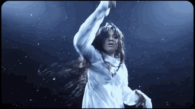 a woman in a white dress is dancing on a stage