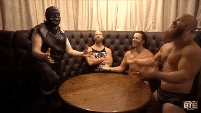 a group of wrestlers are sitting around a table with a bte logo on the table
