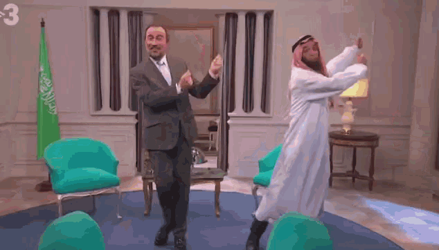a man in a suit and a man in a white robe are dancing in a room with green chairs and the number 3 on the wall