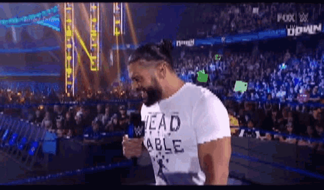 a man wearing a head able t-shirt is standing in front of a crowd .