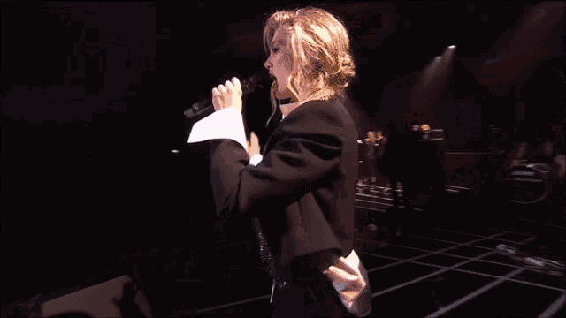 a woman singing into a microphone in front of an audience