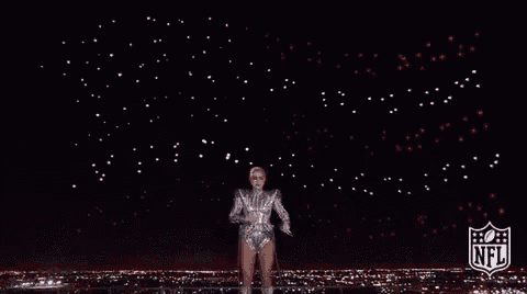 a woman is dancing on a stage with a nfl logo behind her .