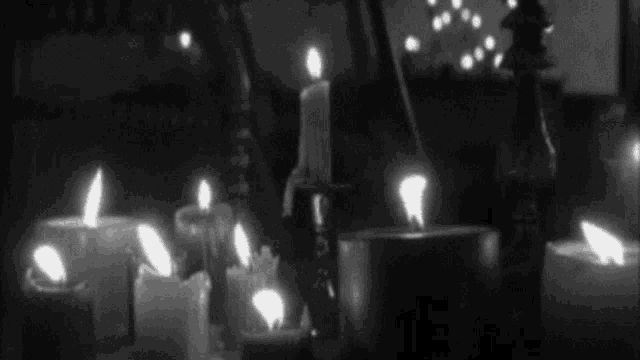 a bunch of lit candles are on a table in a dark room .