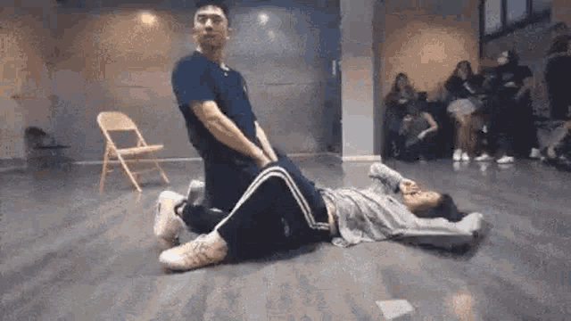 a man is kneeling over a woman laying on the floor in a room .