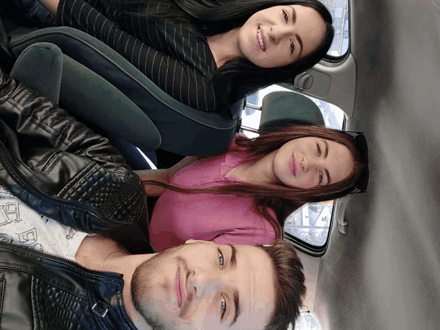 a man and two women laying in the back of a car