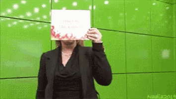 a woman is holding a sign in front of her face