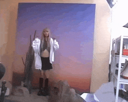 a woman is standing in front of a blue wall in a room holding a hoodie .