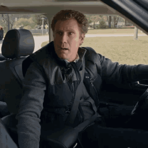 a man is sitting in the driver 's seat of a car and making a funny face