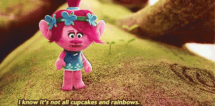 a troll doll is standing on top of a hill and talking about cupcakes and rainbows