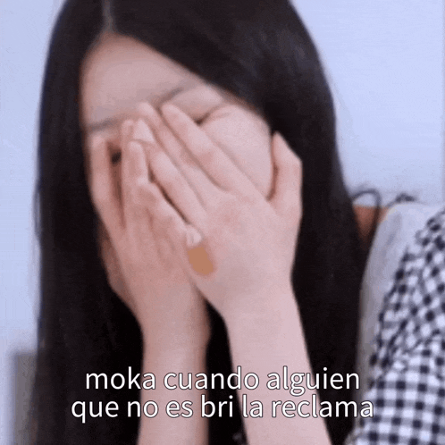 a woman covering her face with her hands with the words moka cuando alguien que no es bri la reclama written below her