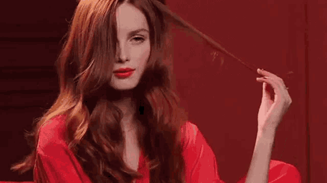 the woman is wearing a red robe and holding her hair .