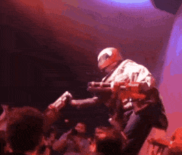 a man in a helmet is playing a guitar in front of a crowd .