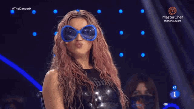 a woman wearing sunglasses and a black top is on a television screen that says masterchef