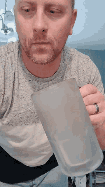 a man with a beard is holding a clear glass mug