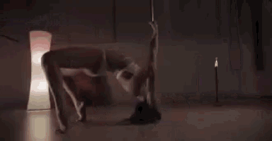 a pole dancer is laying on the floor in a dark room .