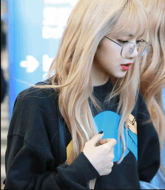 a woman wearing glasses and a black sweater looks down