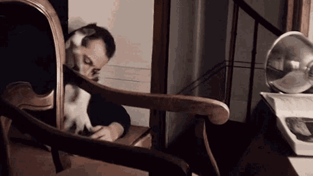 a man is sitting in a chair with a cat on his lap ..