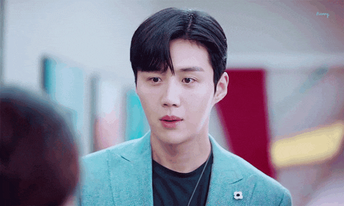 a young man in a blue suit and black shirt is looking at another person .