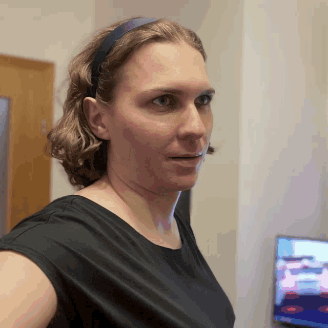 a woman wearing a headband and a black shirt looks to the side