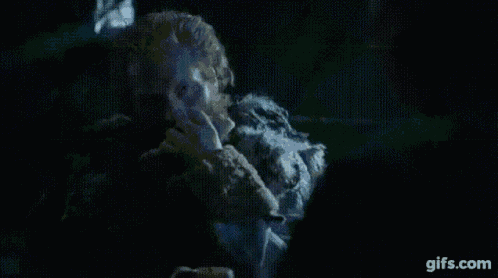 a man with a beard is sitting in a dark room with a glowing object in his hand .
