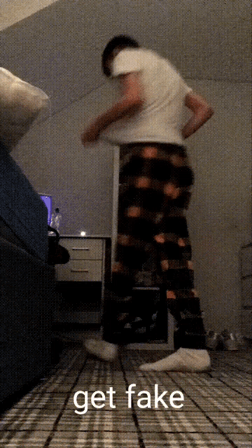 a man in pajamas is dancing in a bedroom with the words get fake on the floor