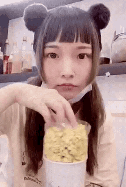 a girl with pigtails is eating popcorn from a bag