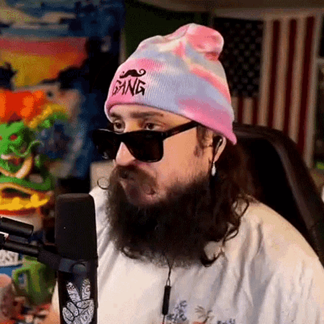 a man with a beard wearing sunglasses and a beanie that says gang on it