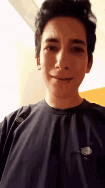 a young man wearing a black t-shirt is smiling for the camera