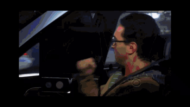 a man sitting in a car with a cbs logo on the hood