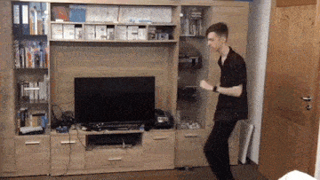 a man is dancing in front of a tv in a room