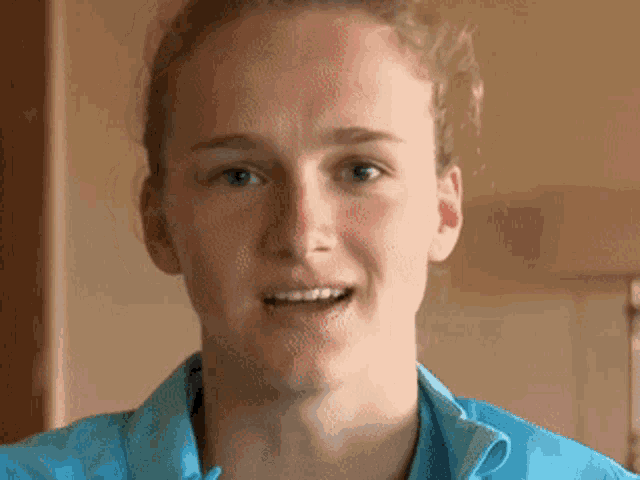 a woman wearing a blue shirt is smiling for the camera
