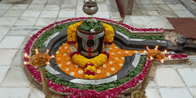 a statue of a deity is surrounded by flowers and candles in a temple