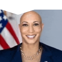 a bald woman is smiling in front of an american flag and wearing a necklace .