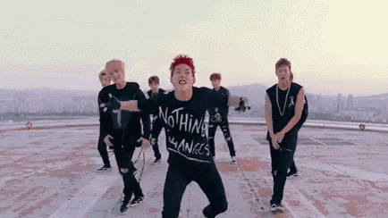 a group of young men are dancing on top of a building .
