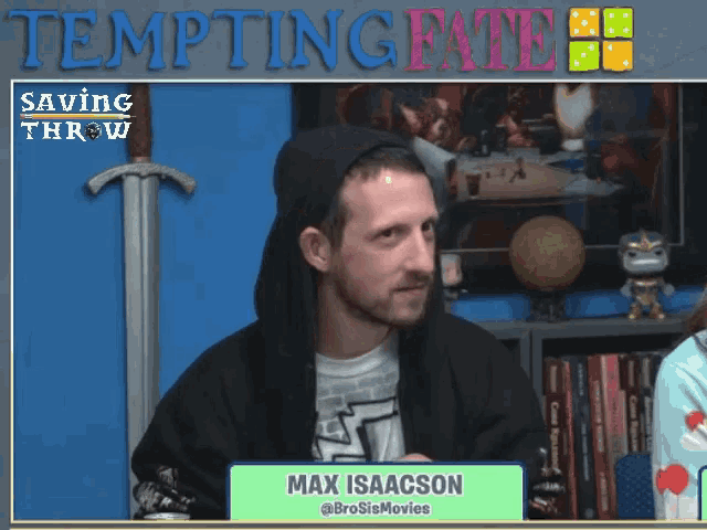 a man in a black hoodie stands in front of a sign that says tempting fate