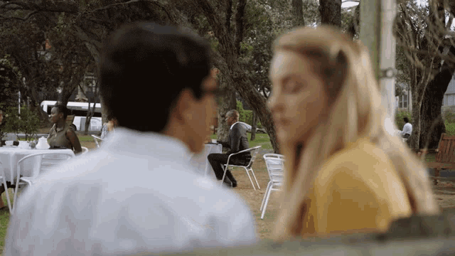 a man and a woman are looking at each other in the park