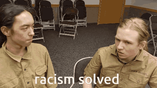 two men are sitting in a room with the words racism solved on the bottom
