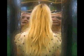 a woman is standing in front of a mirror looking at her reflection .
