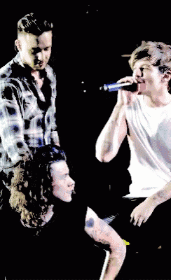 a man in a plaid shirt sings into a microphone while another man looks on