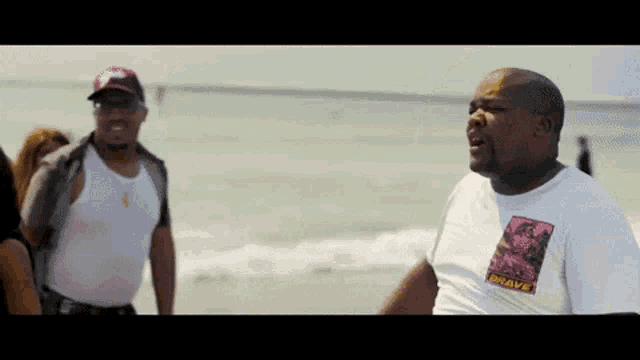 a man wearing a shirt that says mr.wave stands on a beach