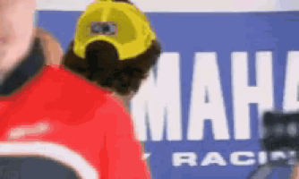 a man wearing a yellow hat is standing in front of a sign that says mahle racing