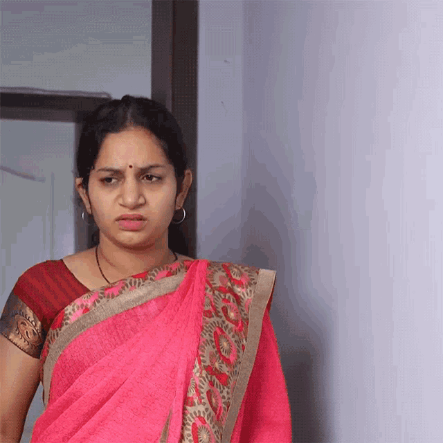 a woman in a pink saree is standing in a doorway