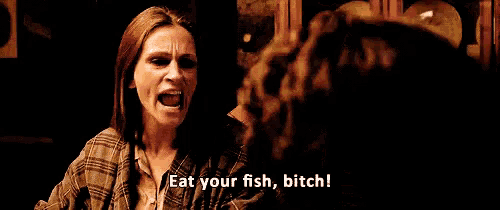 a woman is sitting at a table talking to a man and says eat your fish bitch !