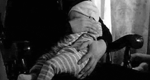 a person is holding a baby in their arms while sitting in a chair .