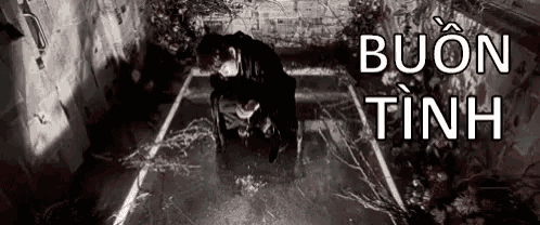a man in a black suit is kneeling down in a dark room .