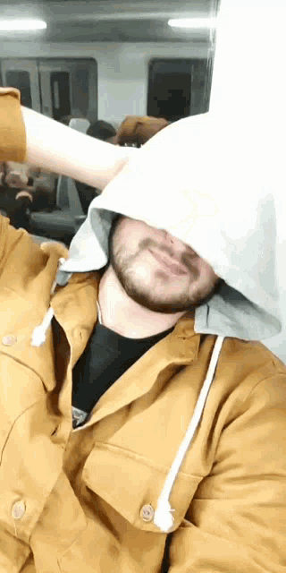 a man with a beard wears a hooded jacket