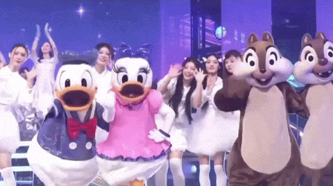 a group of women dressed as donald duck and daisy duck are dancing on a stage .