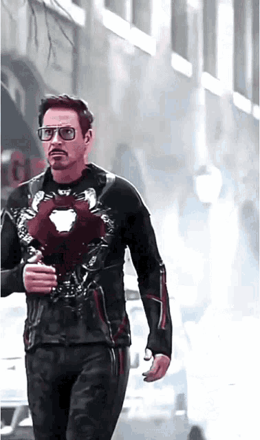 a man wearing glasses and a black jacket is walking down the street
