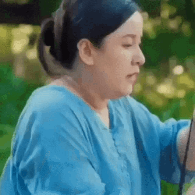 a woman in a blue shirt is taking a picture of herself with a cell phone .