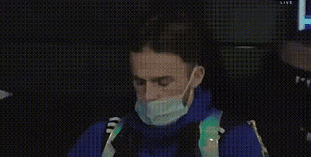 a man wearing a mask is sitting in a chair and looking down .
